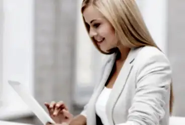 A young woman with blonde hair on her computer booking home cleaning services.